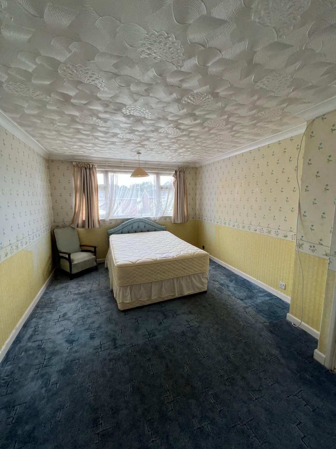The master bedroom as found — blue carpet, floral wallpaper and a textured ceiling